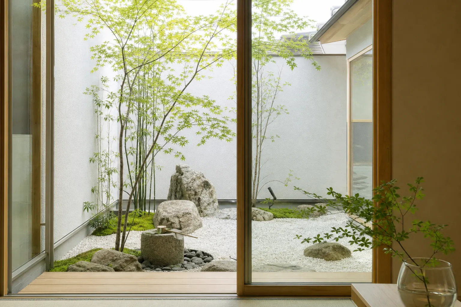 白い砂利と明るい色の竹垣、ヤツデと苔で整えた北側の坪庭の写真