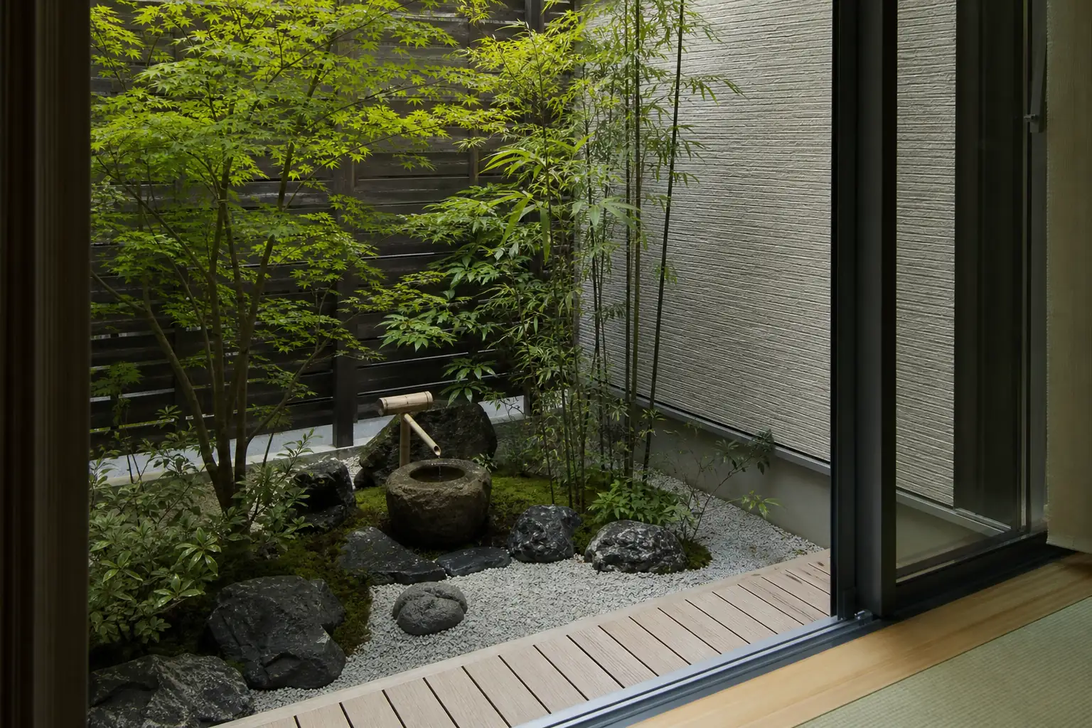 マンションの専用庭に鉢植えの木と砂利の木枠、景石を置いて作った坪庭の写真